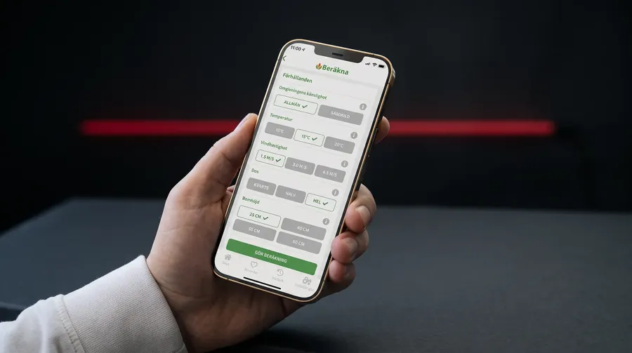 Hand som håller en mobil med Hjälpredan framför ett fält där en traktor sprutar
