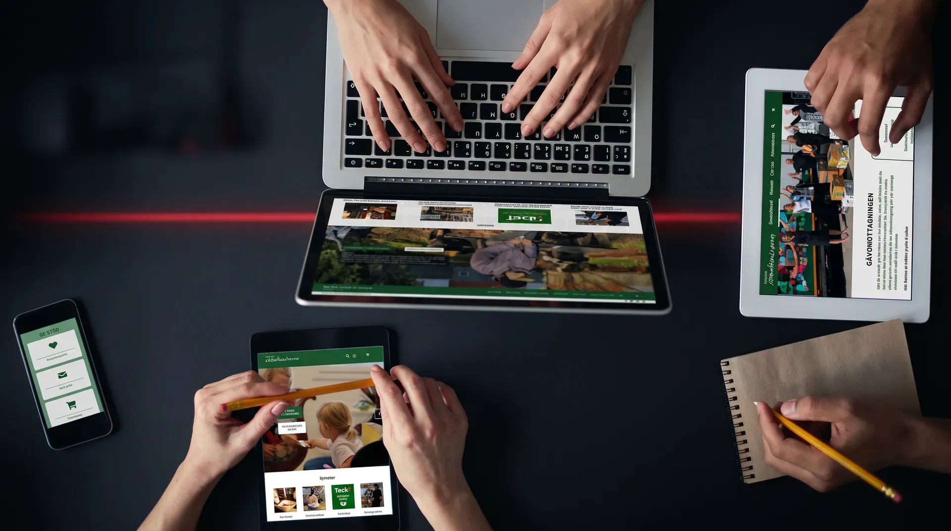 Händer som arbetar vid ett bord med Uppsala Stadsmissions webbplats på laptop, surfplattor och mobil